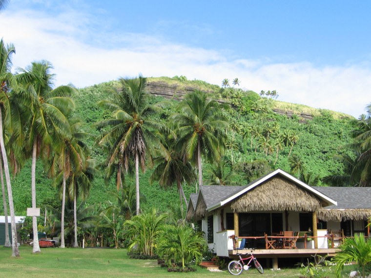 Image: Coconut trees surround beach houses in Aitutaki, Cook Islands